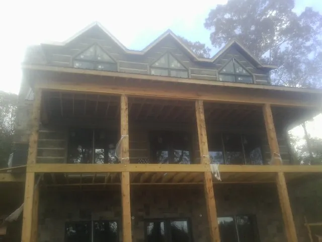 Dormers and porch framing on a large log home under construction — Roof Coating work by our crew in Mitchellville