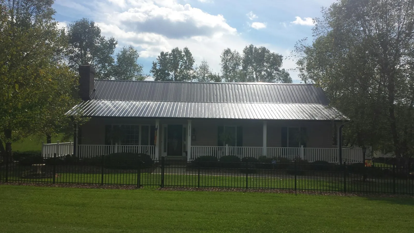 Gray metal roof on a brick ranch with a full width front porch — Gutter Guard Installation work by our crew in Mitchellville