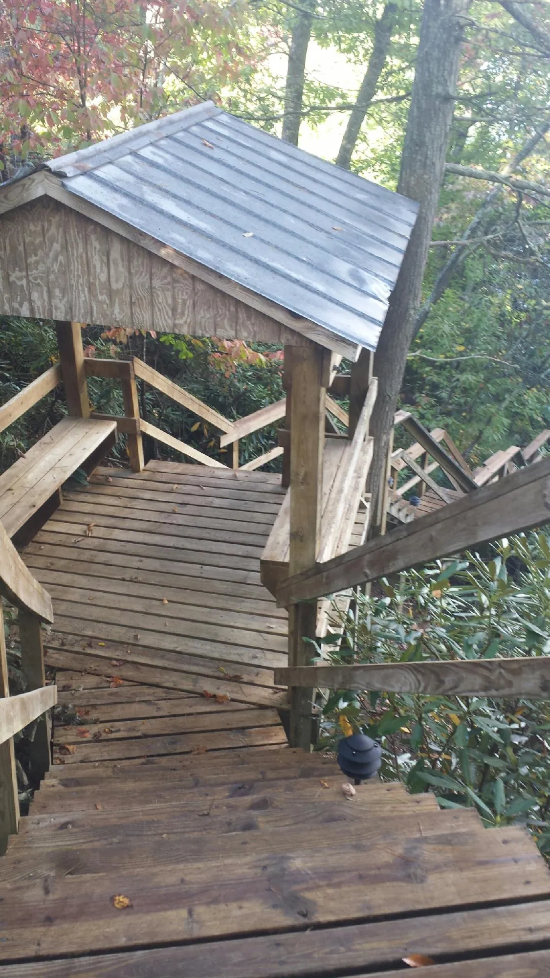 Metal roofed shelter over wooden steps on a wooded walkway — Skylight Repair & Installation work by our crew in Mitchellville