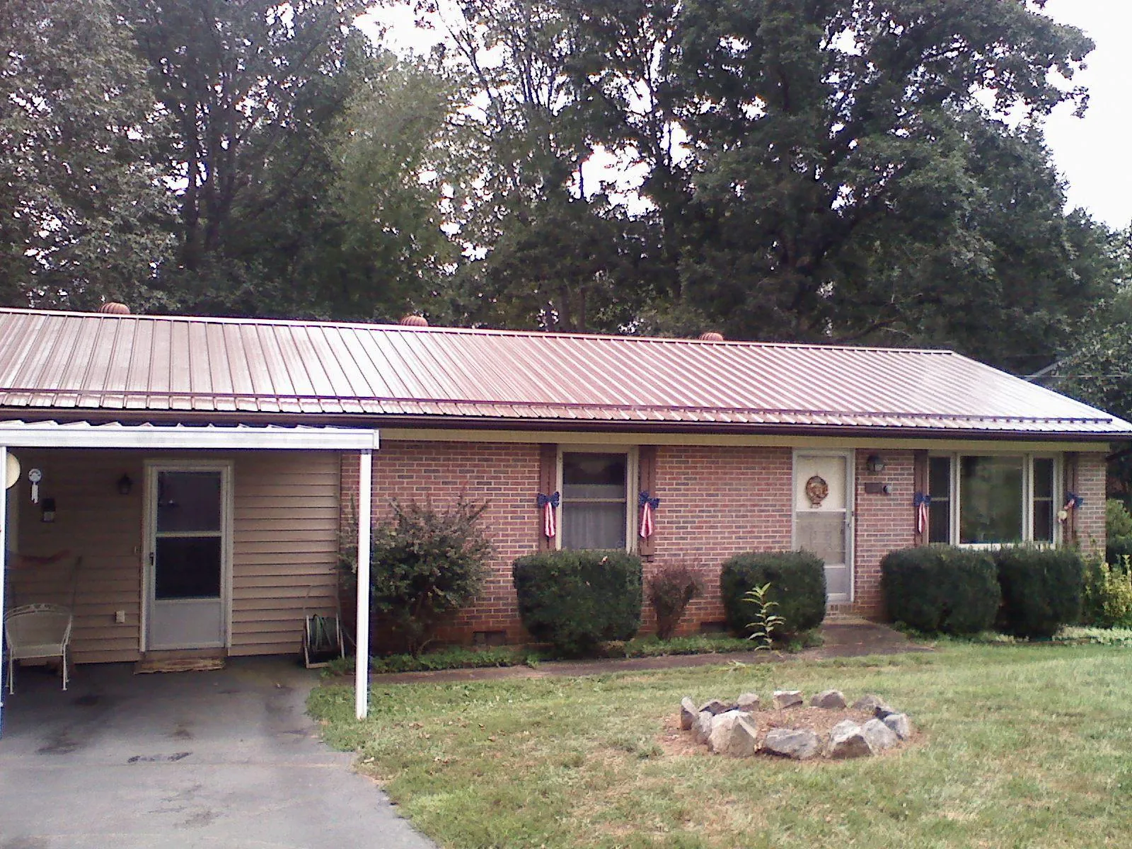 Bronze metal roof and carport on a brick ranch home — Roof Repair work by our crew in Mitchellville