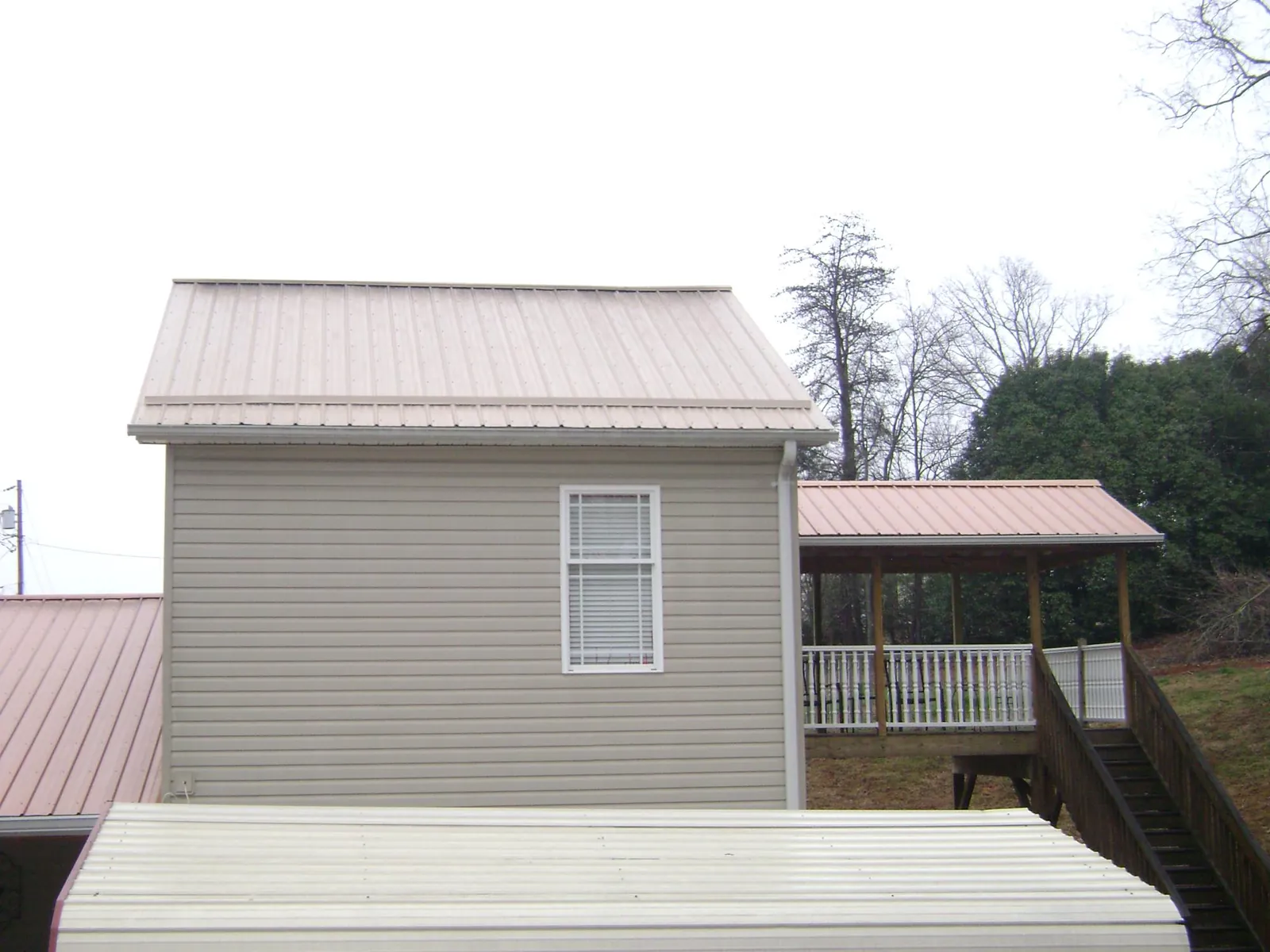 Tan metal roofs on a two story addition and attached porch, from a Roof Replacement job in Mitchellville