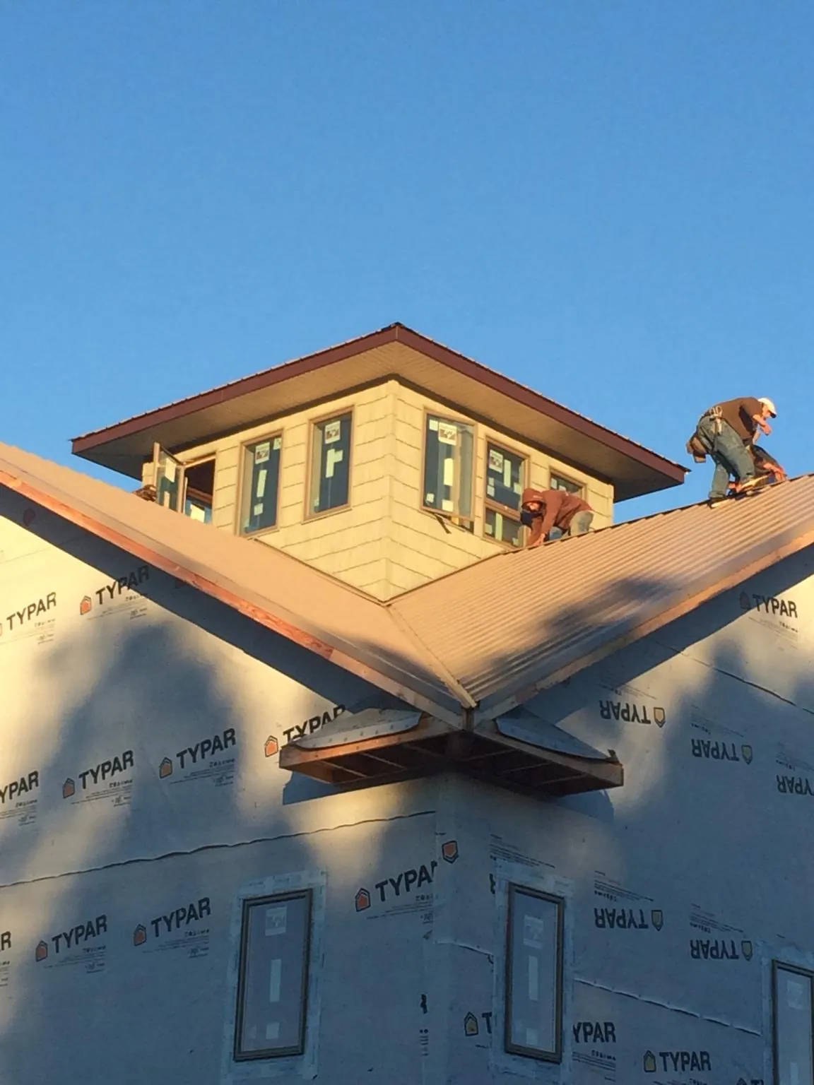 Roofers working around a rooftop cupola on a new metal roof at sunset — Roof Waterproofing in Mitchellville by Roofing Brothers